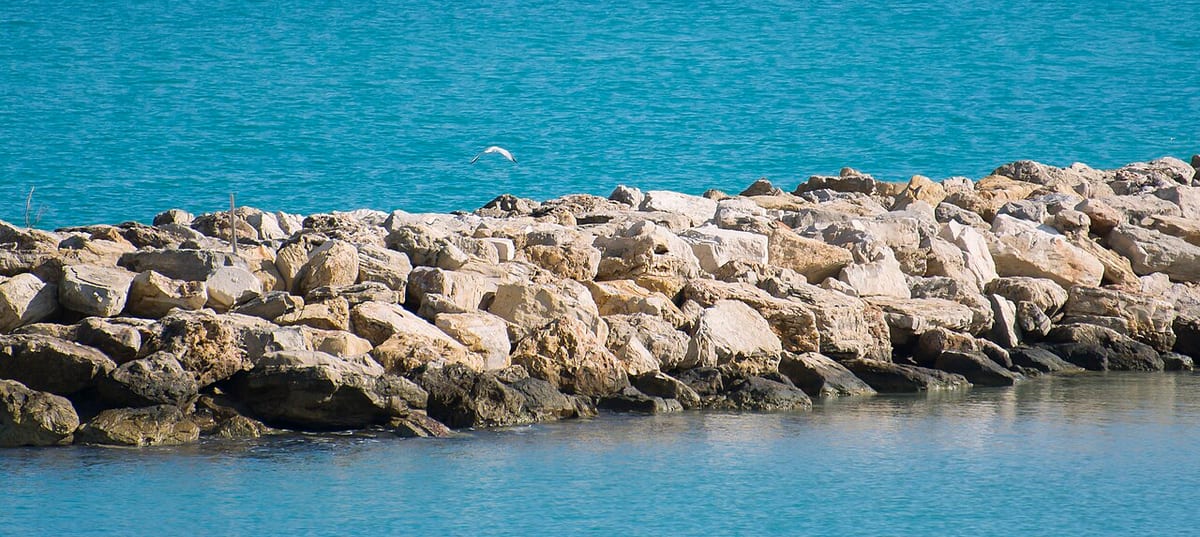 La scogliera frangiflutti e il mare turchese di Campo di Mare, la spiaggia più vicina